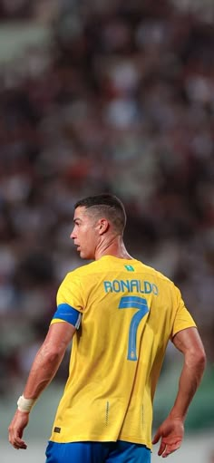 a soccer player in yellow and blue is looking away from the camera with his head down