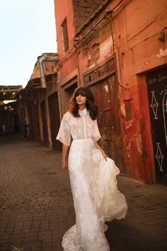 a woman in a white dress is walking down the street