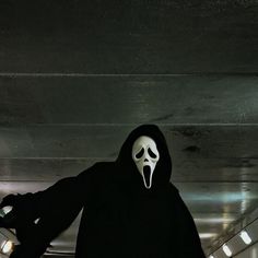 a person in a black hooded suit with a white mask on their face and mouth