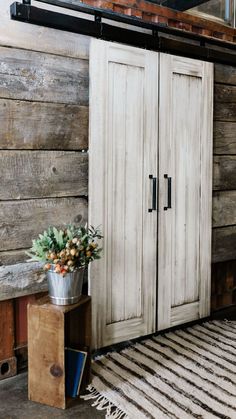 a room with wooden walls and two white cupboards next to a rug on the floor