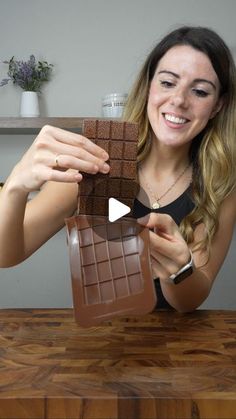 a woman holding up a chocolate bar in front of her face and smiling at the camera