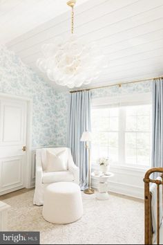 a baby's room with blue and white wallpaper, a chandelier and a rocking chair