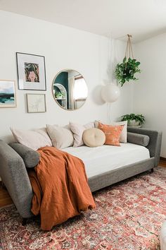 a living room with a couch, mirror and potted plant on the wall next to it