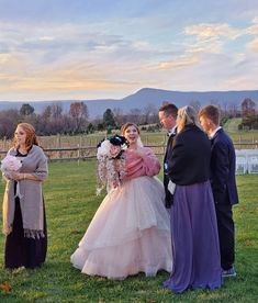 a group of people standing on top of a lush green field next to each other