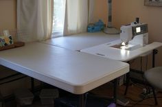 a sewing machine sitting on top of a white table next to a computer desk and chair