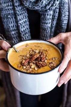 a person holding a bowl of soup with nuts