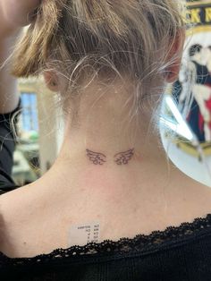 a woman with a tattoo on her neck has a name tag in the shape of an angel