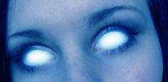 a close up of a person with blue eyes and white lights in their eyes,