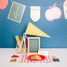 a red plate topped with cookies next to a chalkboard and some paper decorations on a blue wall