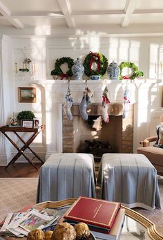 a living room filled with furniture and a fire place covered in wreaths on the mantle