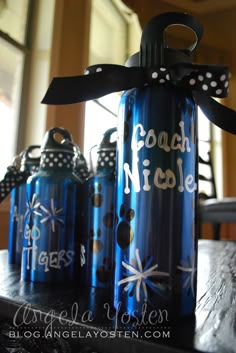 three blue water bottles sitting on top of a table with polka dot ribbon tied around them