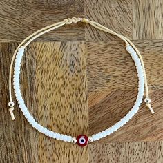 Evil Eye Adjustable White Seed Cord Bracelet, Macrame Sliding knot, Red Eye Protection Gift for Her/Him - Birthday, Friendship, Family, Colleague Adorable handmade adjustable Evil Eye bracelet featuring a 6 mm Evil Eye red glass bead, white glass seeds and golden glass seeds. These have been carefully threaded onto a beige nylon cord.  Traditionally, the Evil Eye is said to protect the wearer against negative energy or the power of evil. This lovely bracelet would make the perfect gift for a fri Adjustable Cord Bracelet, Bracelet Macrame, Bracelet Cordon, Red Eye, Cord Bracelet, Sliding Knot, Eye Bracelet, Resin Beads, Evil Eye Bracelet