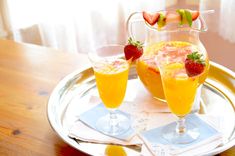 two glasses filled with orange juice and strawberries