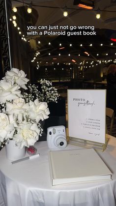 a white table with flowers and a book on it that says, you can just not go wrong with a polaroid guest book