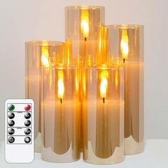 a group of candles sitting next to each other on top of a white table with remote controls