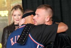 two people embracing each other in front of a black background