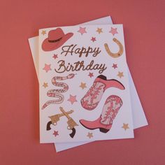 a happy birthday card with cowboy boots and western hats on it, sitting on a pink surface