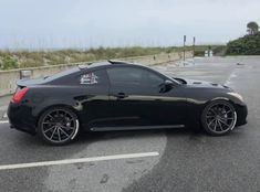 a black sports car parked in a parking lot next to an empty road with no cars on it