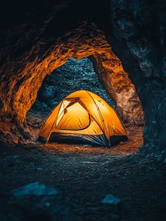 a tent is set up in the middle of a cave with its light shining on it