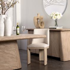 a dining room table with two chairs and vases on top of it, in front of a mirror