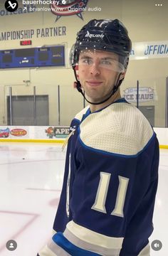 a hockey player is standing in front of an ice rink with his helmet on and looking at the camera