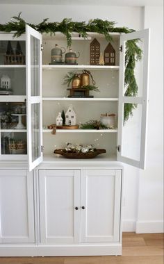 a white china cabinet with christmas greenery on top