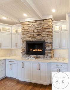 a kitchen with white cabinets and a stone fireplace