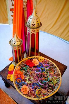 a basket filled with lots of colorful rings on top of a wooden table next to candles