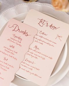 two pink menu cards sitting on top of a white plate