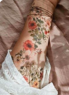 a woman's arm with flowers on it and a white dress underneath her leg