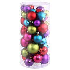 a glass vase filled with lots of colorful christmas ornament ornaments on white background