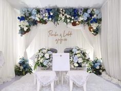 a table and chairs are set up in front of a backdrop with flowers on it