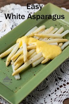 a green plate topped with french fries covered in white asparagus sauce on top of a doily