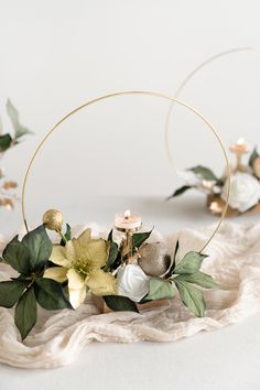 a white cake with flowers and greenery on it's side, surrounded by gold hoop