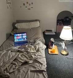 a laptop computer sitting on top of a bed next to a lamp and other items