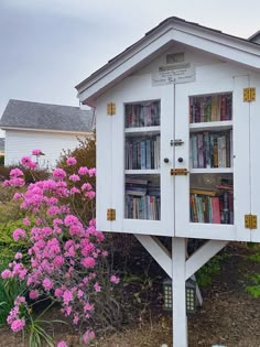 there is a small white book shelf in the shape of a house with books on it