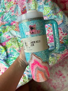 someone is holding up a cup with glitter on it and the lid has a unicorn print