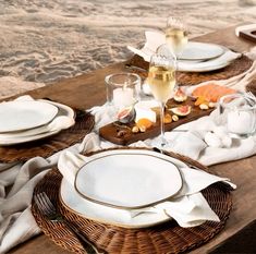 the table is set with white plates and silverware on it, along with wine glasses