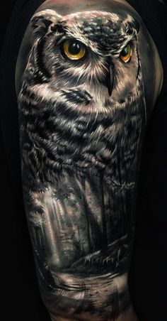 an owl with yellow eyes is shown on the back of a man's arm