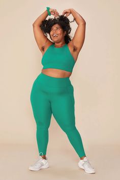 a woman in a green sports bra top and matching leggings poses for the camera