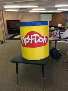 a large yellow bucket sitting on top of a black table in an office space with other desks and chairs