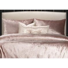 a bed covered in pink and white sheets with pillows on top of the headboard