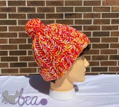 a mannequin head wearing a red and yellow knitted hat on top of a white table