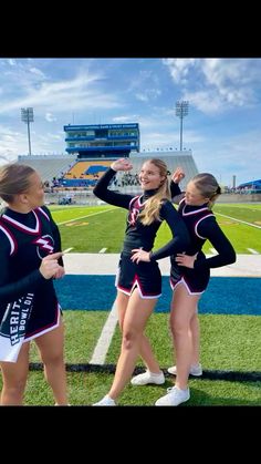 three cheerleaders standing on the sidelines at a football game