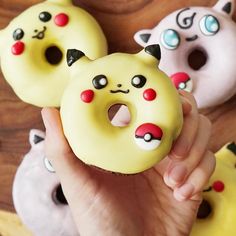 a person is holding up some donuts with faces on them and they are decorated like cats