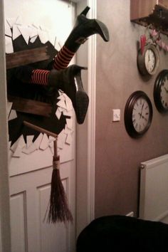 a halloween decoration is hanging on the wall in front of a door with clocks and brooms