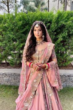 a woman in a pink bridal gown with her hands on her hips, posing for the