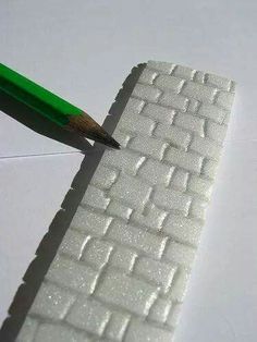 a green pencil sticking out of the side of a white piece of paper with small squares on it