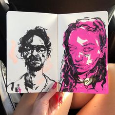 a woman's hand holding an open notebook with two drawings of people on it