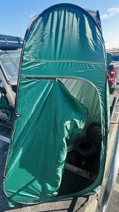 a green tent sitting in the back of a truck with it's door open